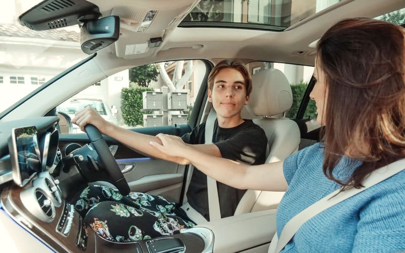 A parent in the passenger seat while their teenager practises driving