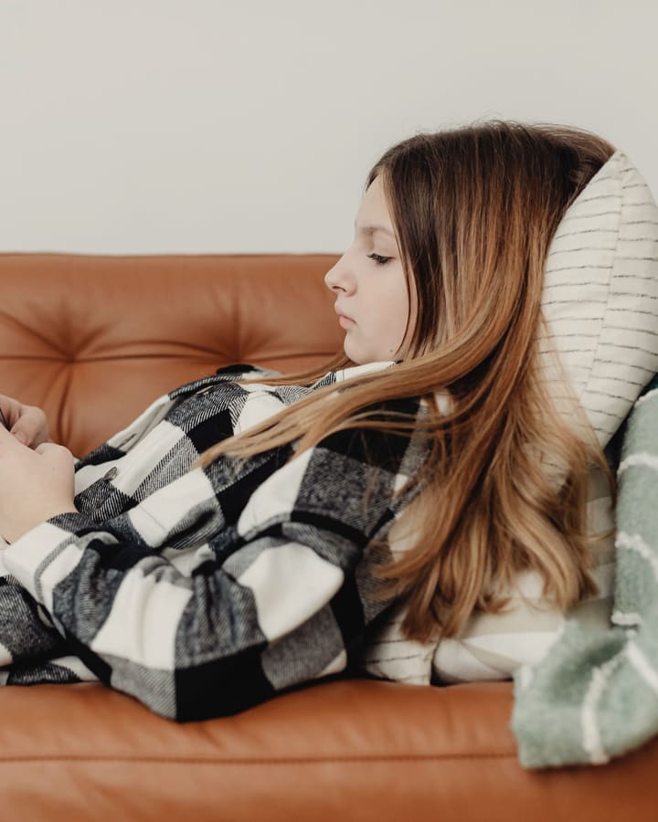 A learner on the sofa going through questions on her phone